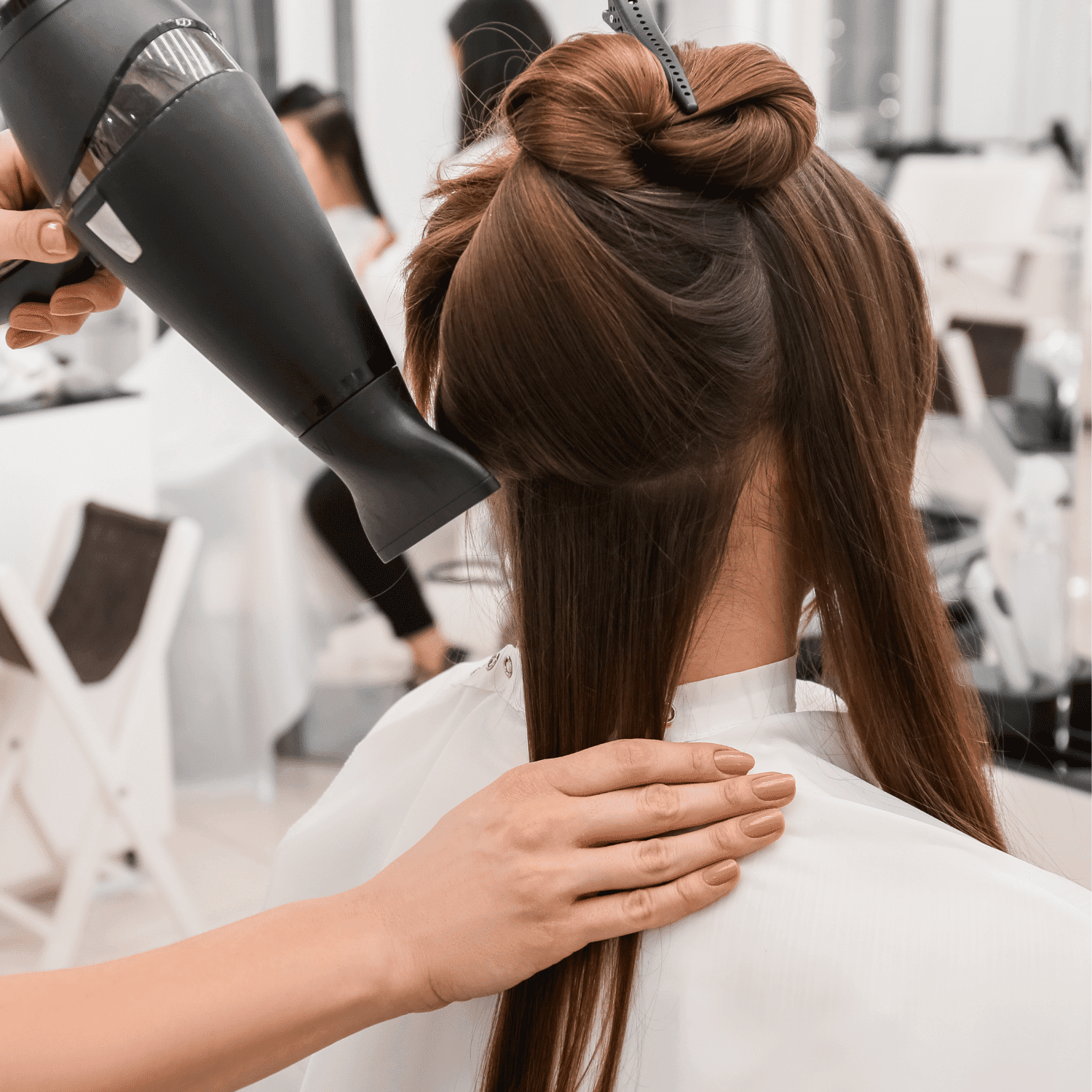 Hair stylist blow-drying and styling a client's hair in a salon.