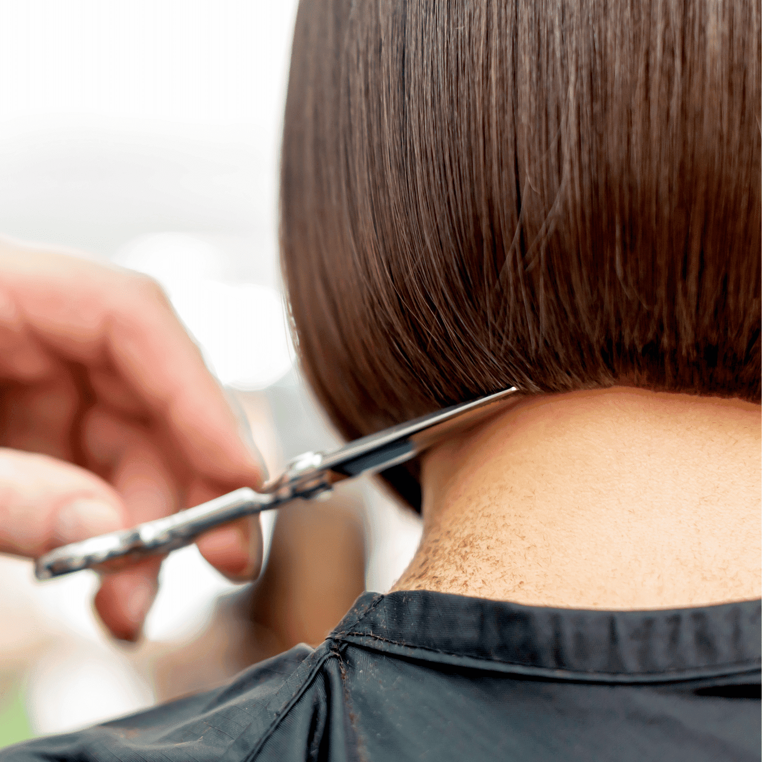 Hairdresser cutting a client's hair into a sleek, straight bob haircut.